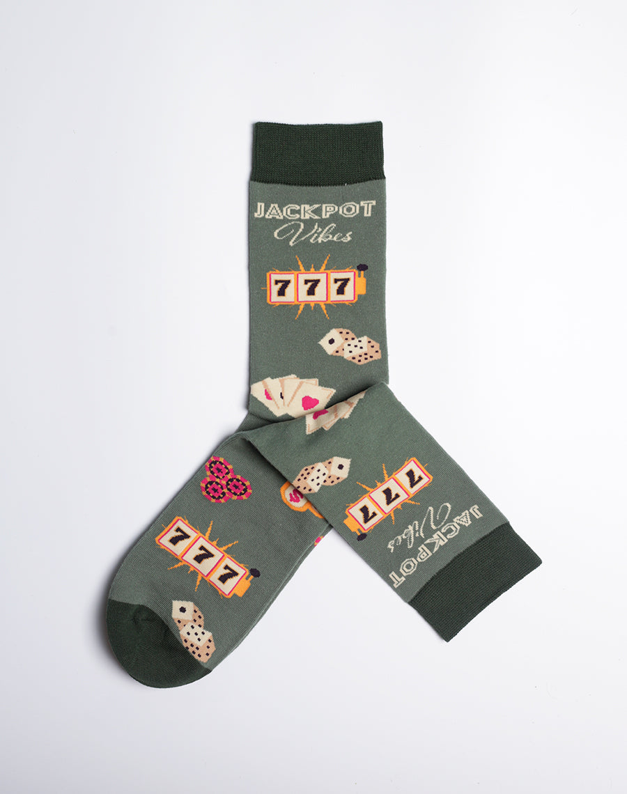 Men's crew socks in dark green featuring a Las Vegas casino theme with 'Jackpot Vibes', slot machines, playing cards, and dice designs.